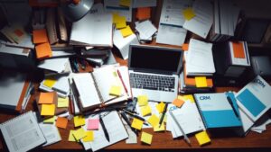 Een rommelig kantoorbureau met CRM-gerelateerde items.